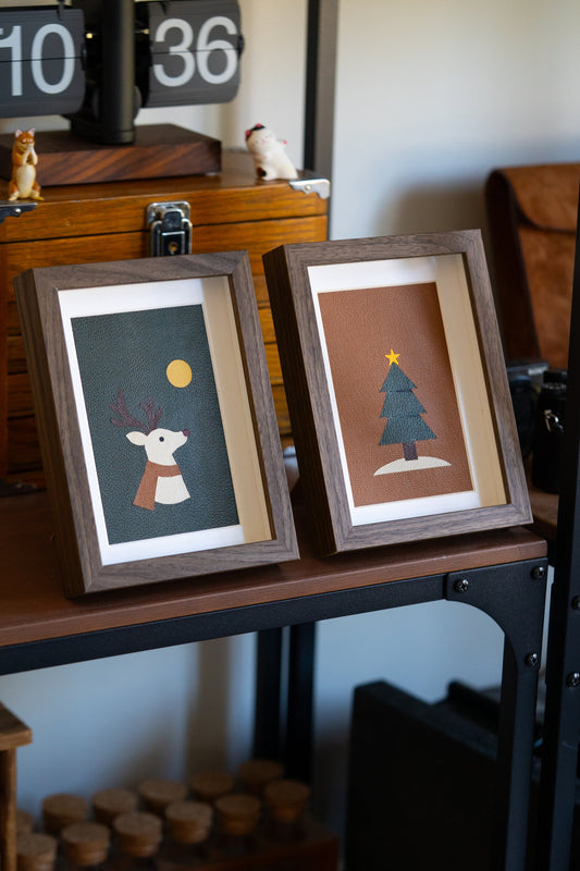 Reindeer and Christmas Tree leather art side by side on a shelf