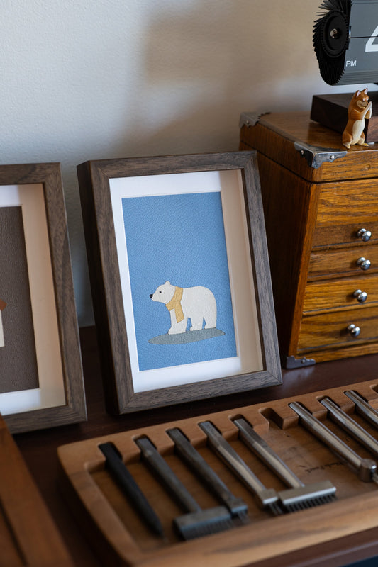 Angled view of the framed Polar Bear leather art on a studio desk